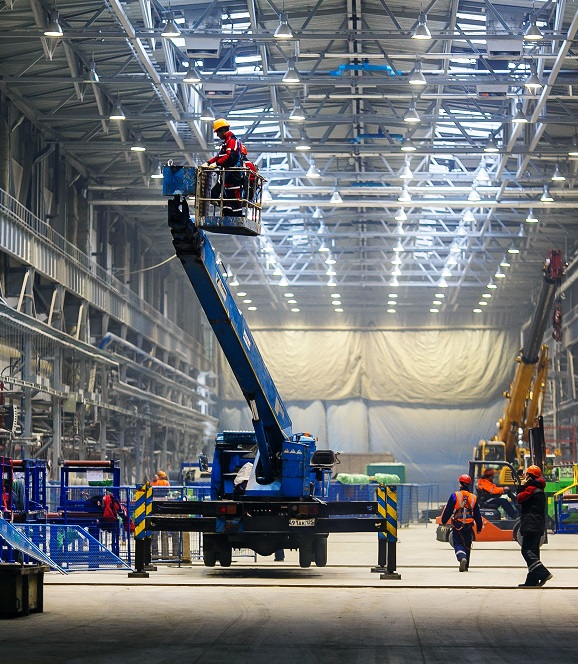 man on cherry picker in manufacturing plant